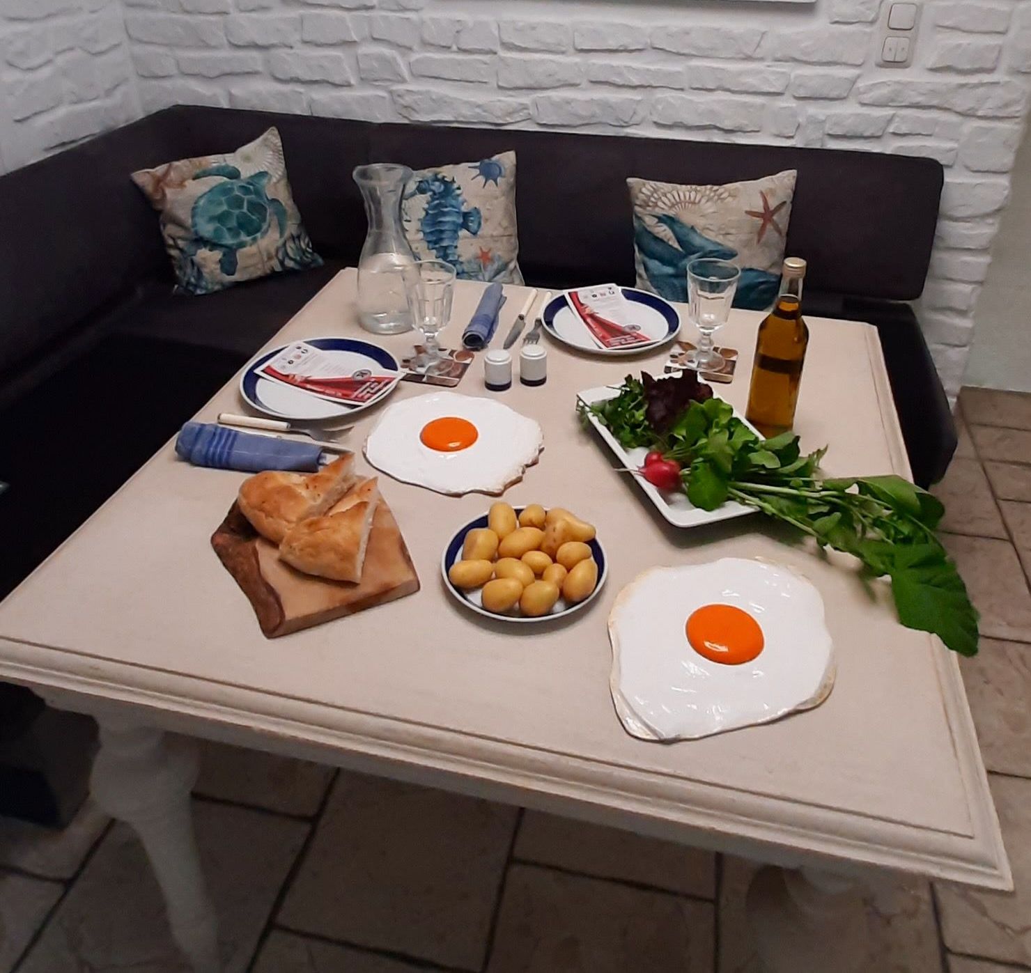 Sunny side up by Oliver Pohl - Tischdeko Zwei plastisch gestaltete und bemalte Spiegleier aus Holz von Bildhauer Oliver Pohl. Sie liegen als Deko auf einem gedeckten Esstisch.