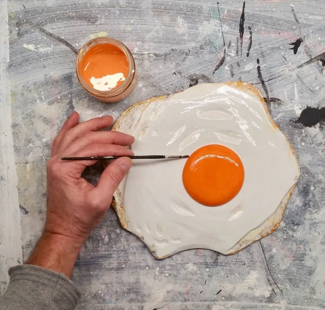 Sunny side up by Oliver Pohl - Tischdeko Zwei plastisch gestaltete und bemalte Spiegleier aus Holz von Bildhauer Oliver Pohl. Sie liegen als Deko auf einem gedeckten Esstisch.