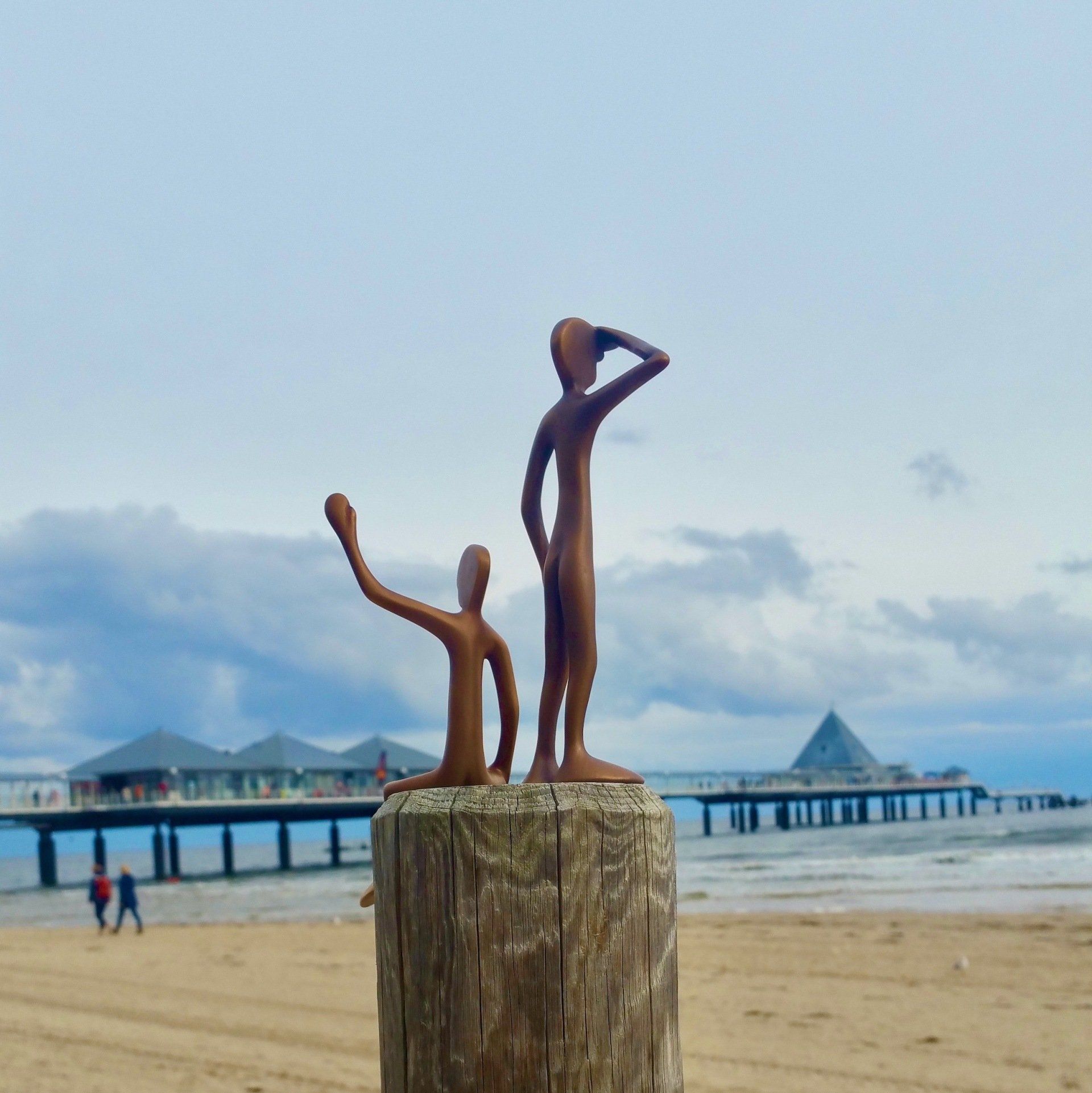 Das Bild zeigt die Bronzefriends No 1 und No 2 von Bildhauer Oliver Pohl. Er steht am Strand von Heringsdorf und im Hintergrund ist die Ostsee zu sehen