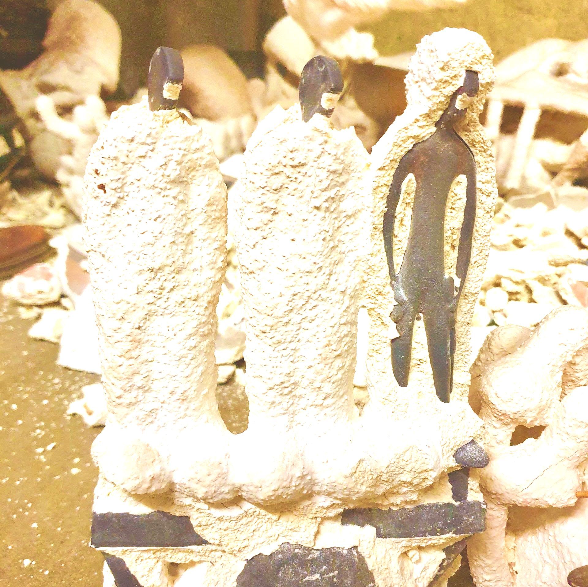 Das Bild zeigt Keramikformen mit Rohgüssen in Bronze, unmittelbar nach dem Guss. Die Figuren sind noch völlig unbearbeitet.