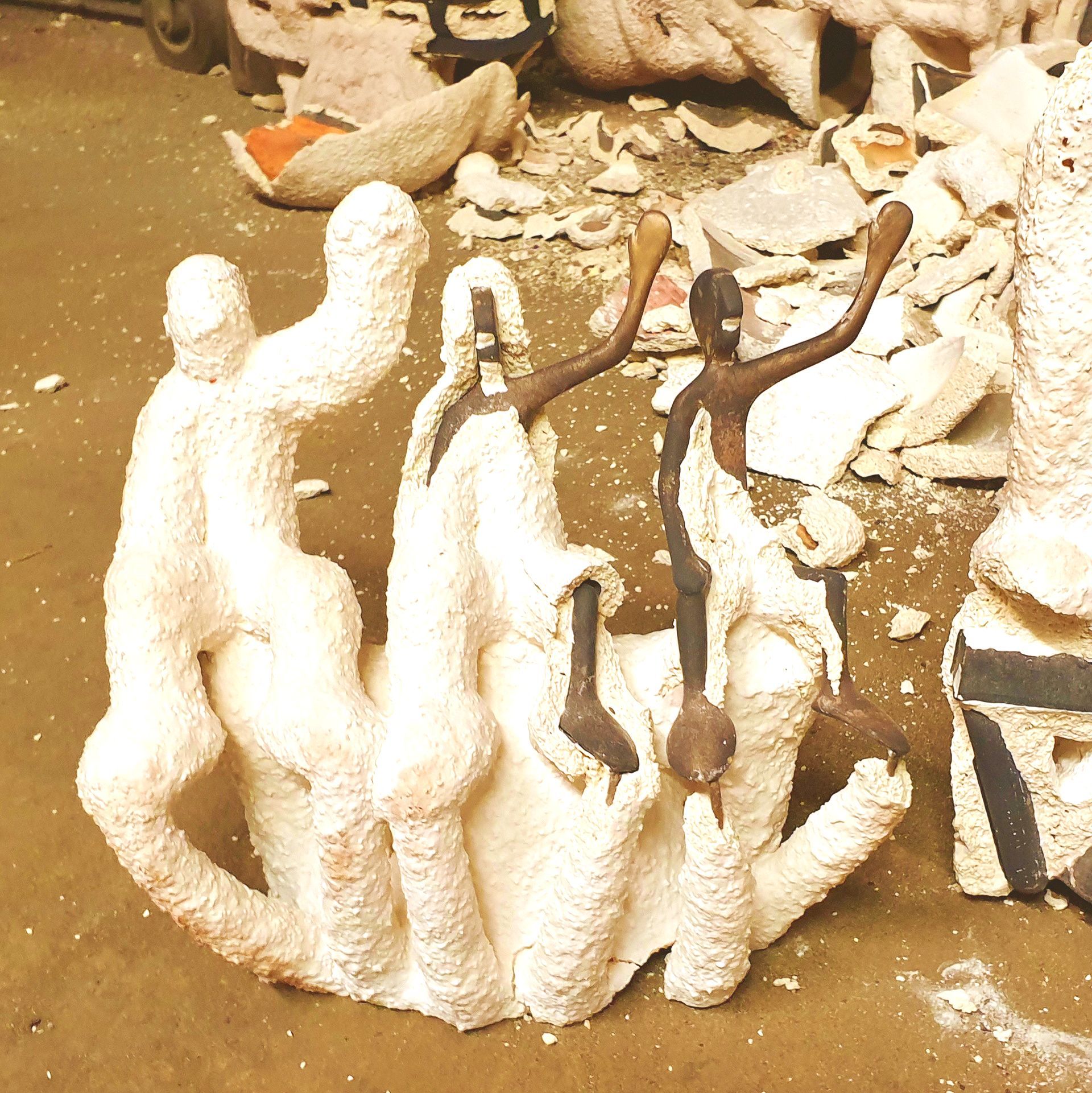 Das Bild zeigt Keramikformen mit Rohgüssen in Bronze, unmittelbar nach dem Guss. Die Figuren sind noch völlig unbearbeitet.