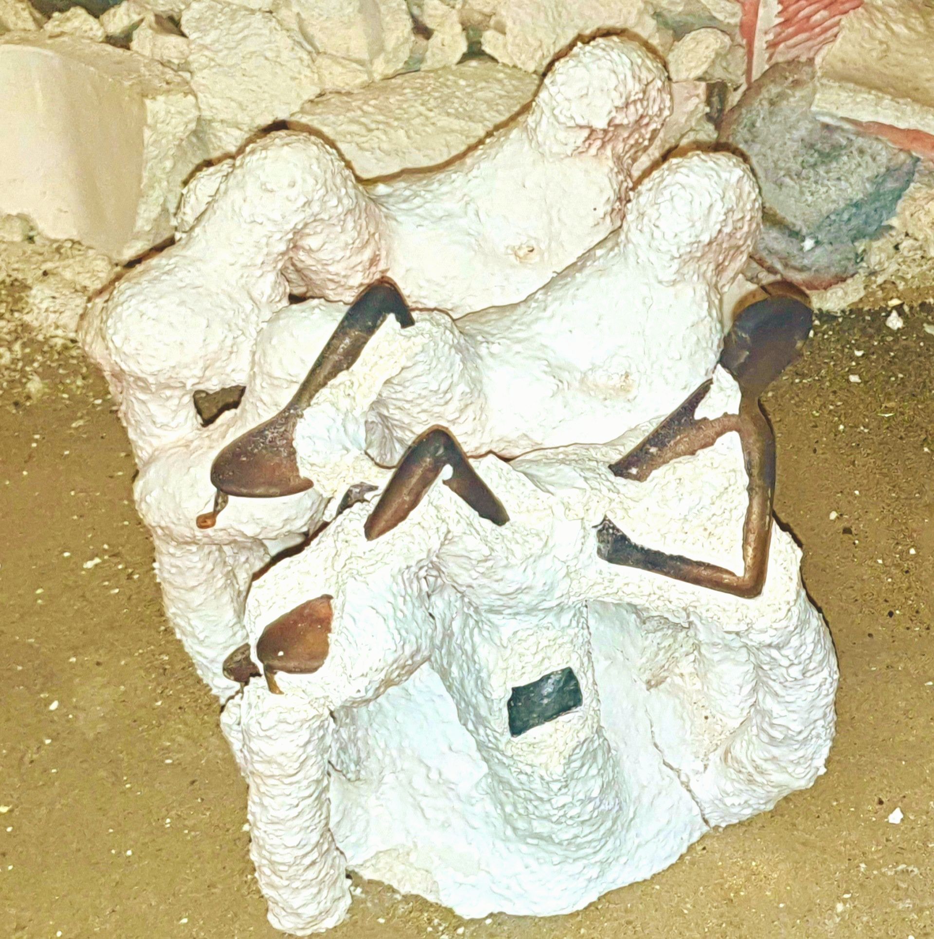 Das Bild zeigt Keramikformen mit Rohgüssen in Bronze, unmittelbar nach dem Guss. Die Figuren sind noch völlig unbearbeitet.