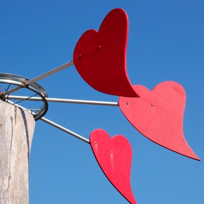 Das Bild zeigt ein bunt bemaltes Windspiel mit roten Herzen im Künstlergarten von Oliver Pohl in Haste bei Bad Nenndorf.