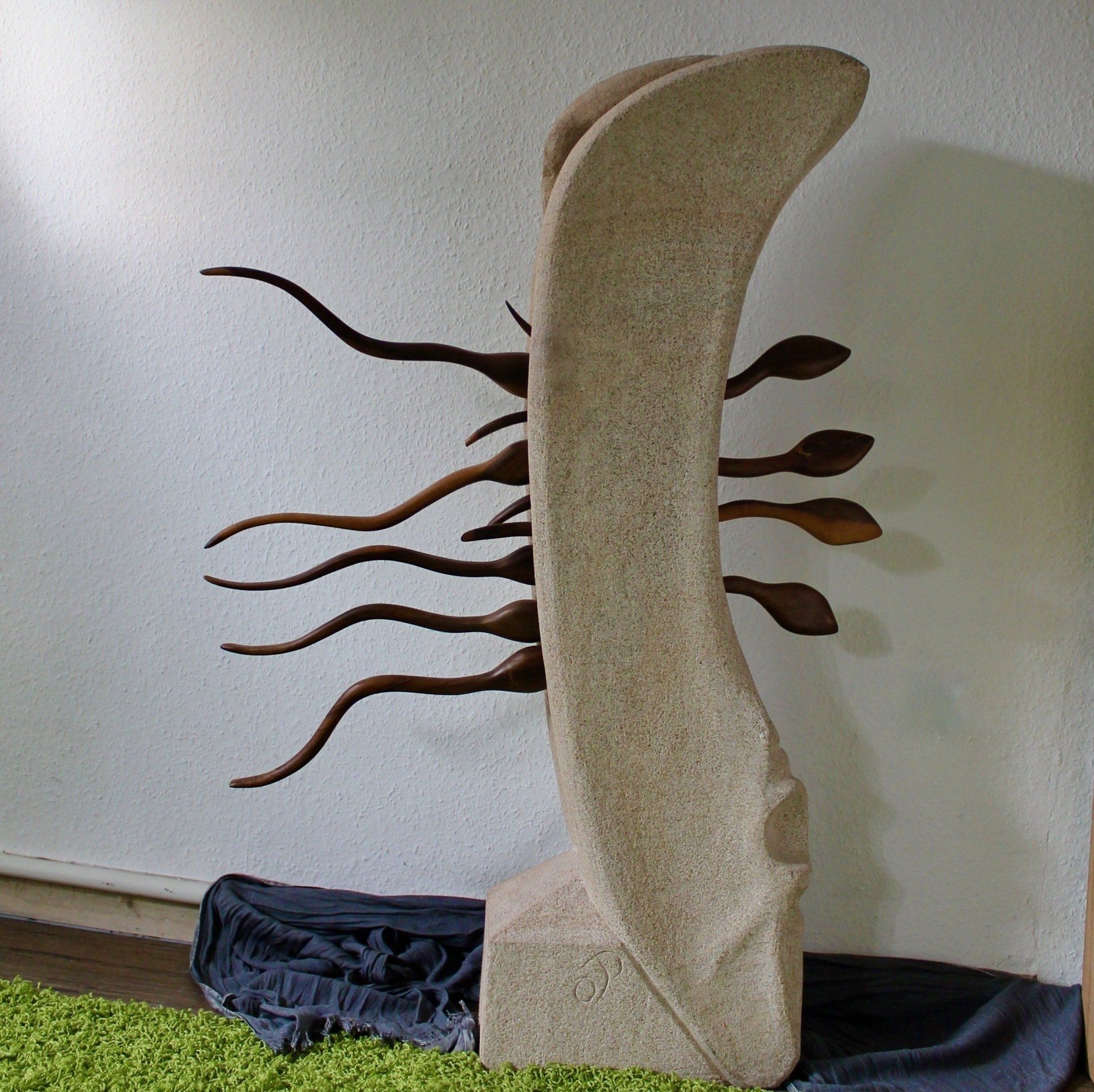 Das Bild zeigt eine große Holz- und Sandsteinskulptur mit dem Titel