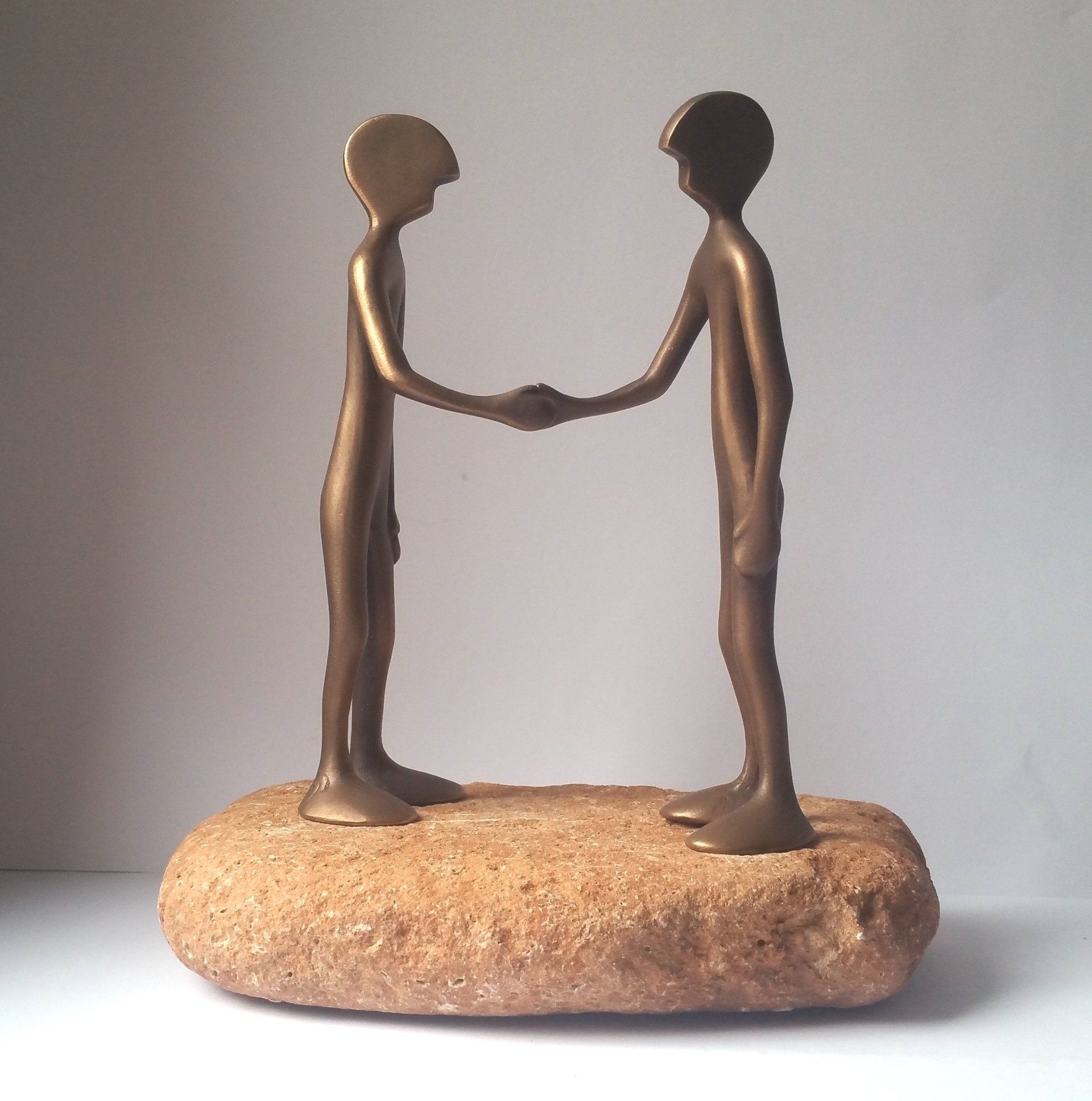 Das Bild zeigt zwei Bronze-Figuren der Serie Friends von Bildhauer Oliver Pohl aus Haste im Schaumburger Land. Sie stehen auf einem Steinsockel und schütteln sich die Hände.