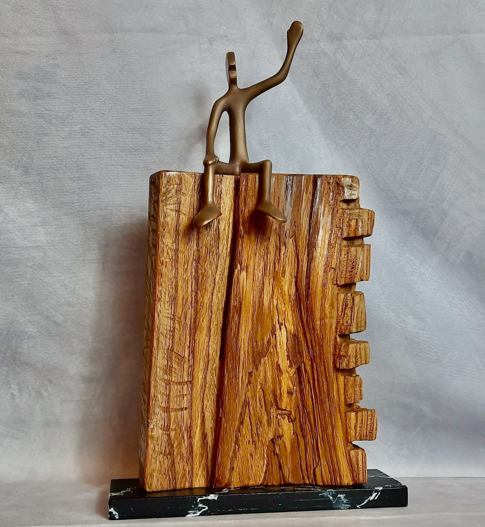 Unikat in Holz und Bronze FRIEND No 2 Kleine Bronzefigur der Serie Friends von Bildhauer Oliver Pohl, sitzend auf einem Ulmenholzsockel. Sie winkt dem Betrachter zu.