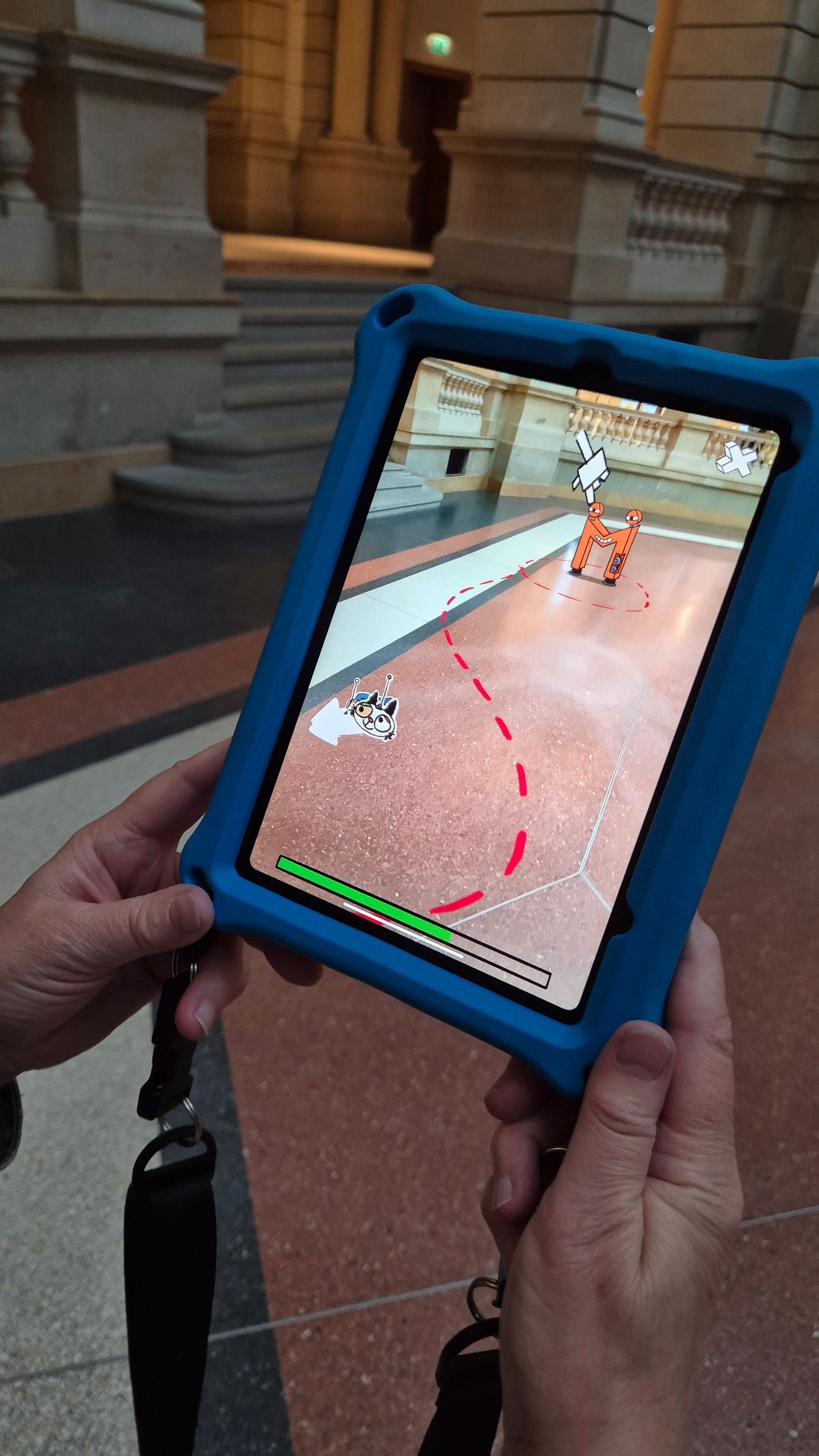 Eine Hand hält ein Tablet in den Raum. Auf dem Monitor ist eine rot gestrichelte Linie, die zu einem lustigen Wesen in Form eines