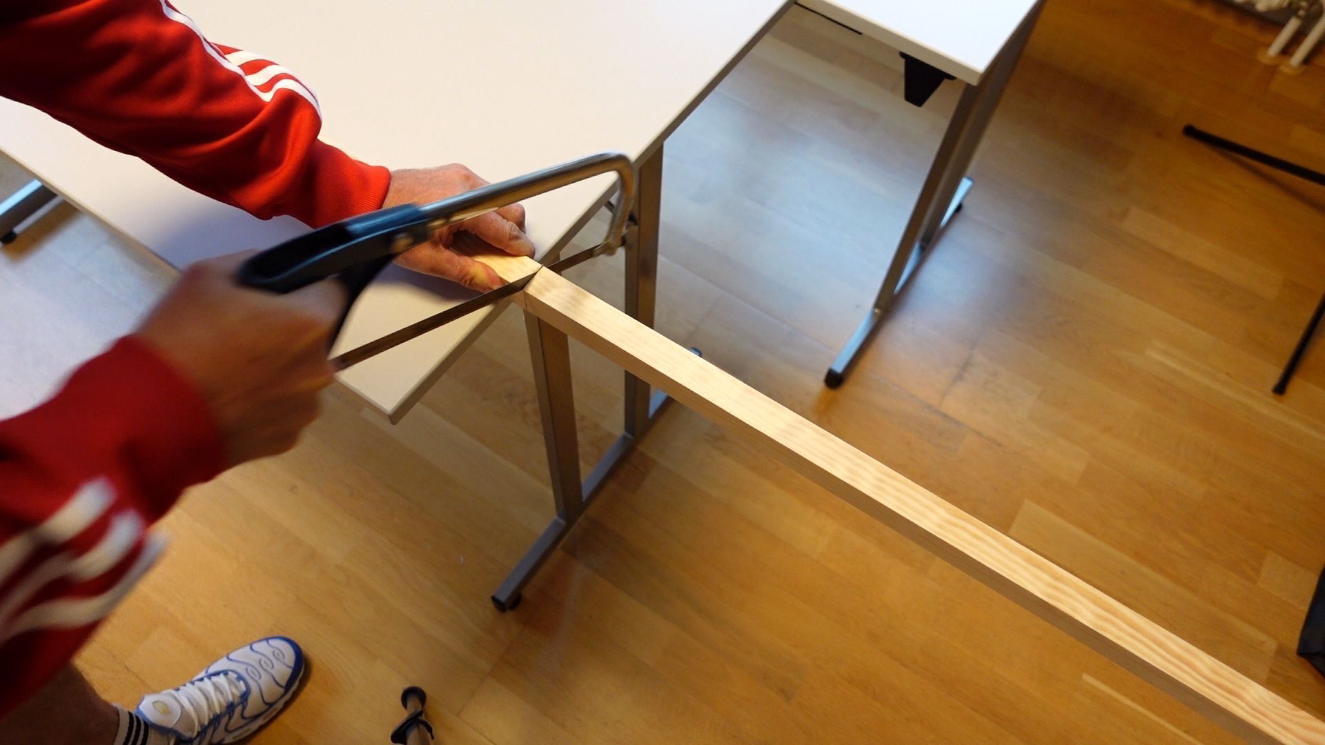 Eine Holzleiste zum Bau eines Boomwhackers Röhreninstrumentes wird abgesägt
