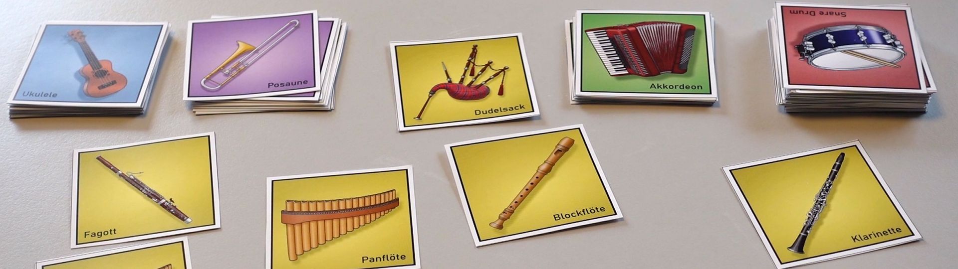 Memo Legespiel aus Papier Instrumentenkarten, farblich nach Instrumentengruppen sortiert. Holzblasinstrumente, Blechblsainstrumente, Saiteninstrumente und Percussion