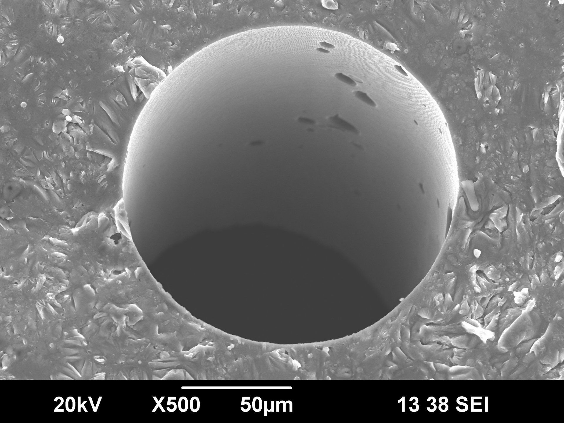 Laser micro-drilled hole in additive manufactured aluminum, detailed view. Pores are visible.
