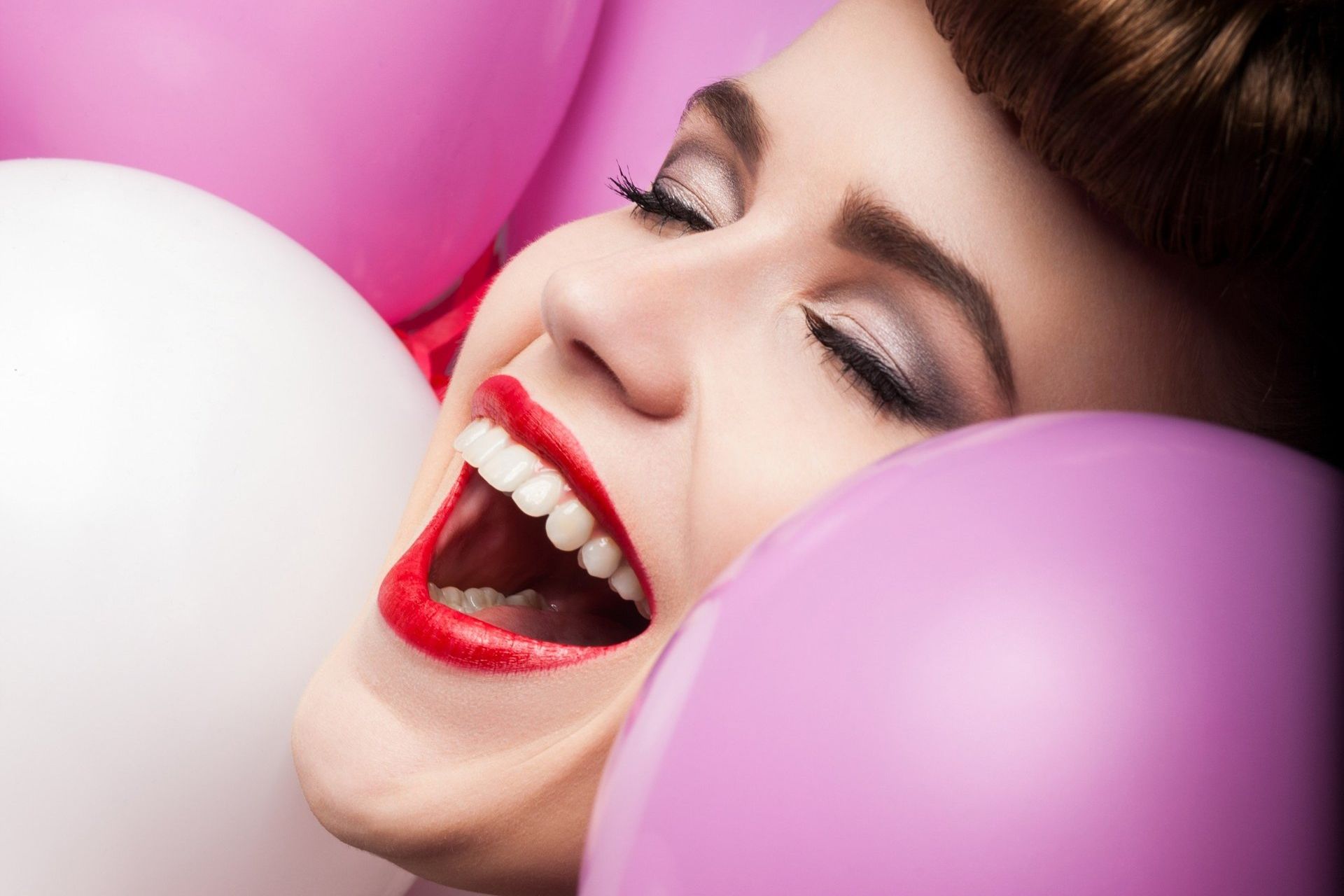 Lachendes Gesicht einer Frau zwischen lila Luftballons