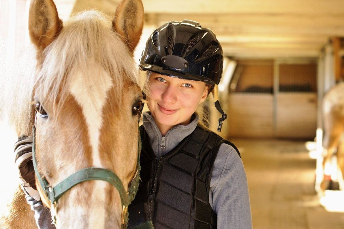 Teenagerin mit Pferd im Stall