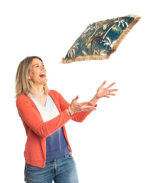 Frau wirft Kissen in die Luft