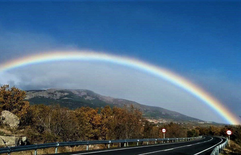 arco iris que se abre en el camino, como una esperanza de luz y color después de las nubes