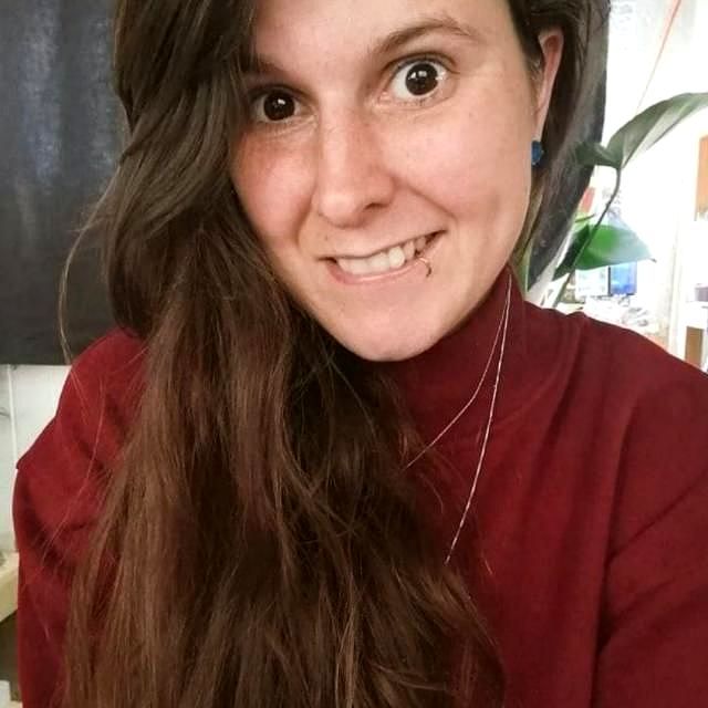 a photo of rose wyles - the vegan nutritionist wearing a red jumper, smiling, and with her long brown hair