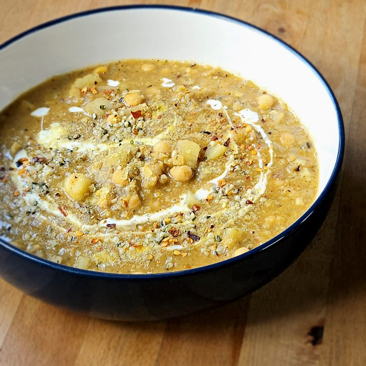chickpea and potato soup in a metal dish topped with fresh basil and sourdough toast.