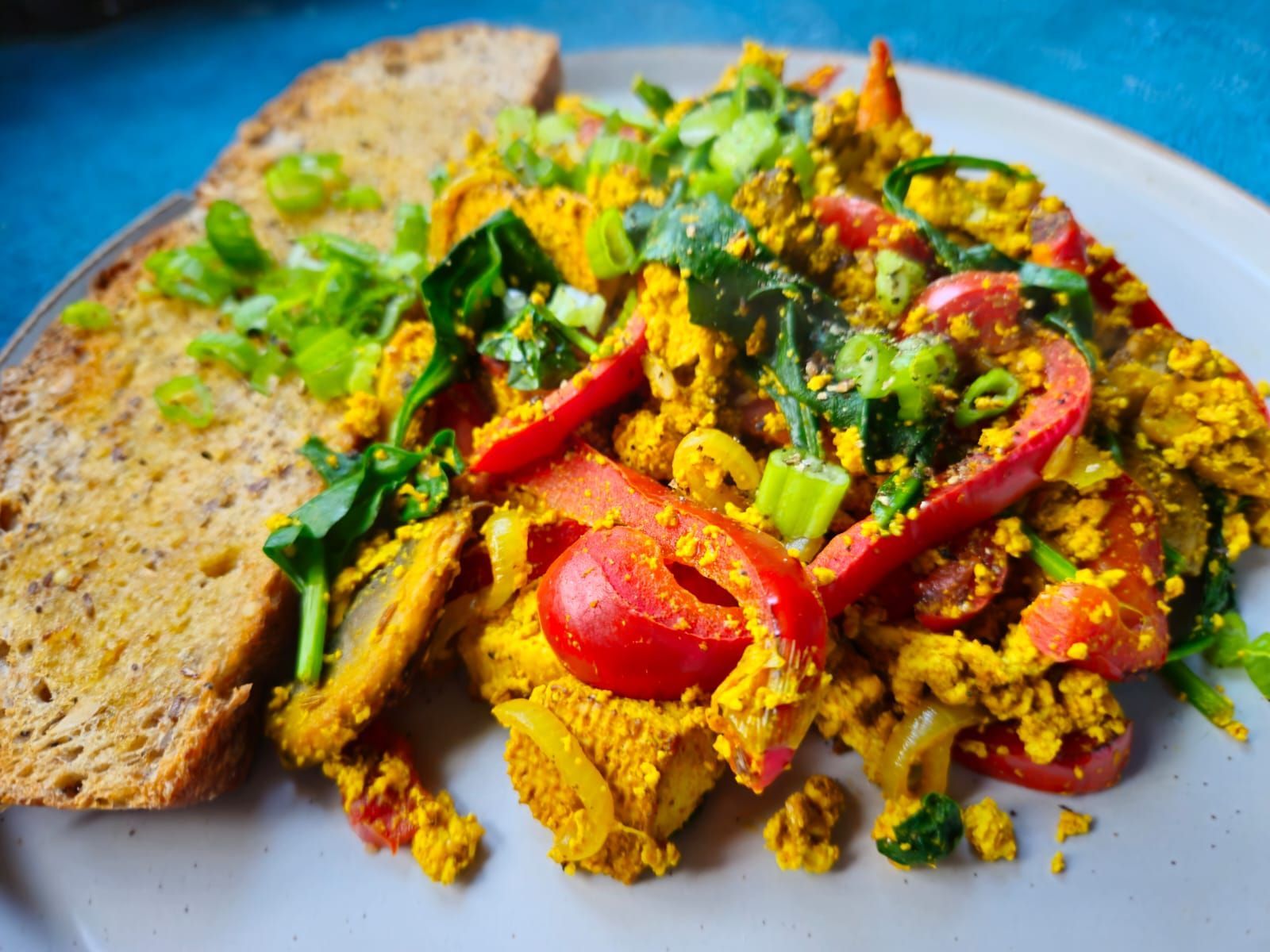 Smoked tofo scramble on a plate with bell pepper and a slice of buttered toast