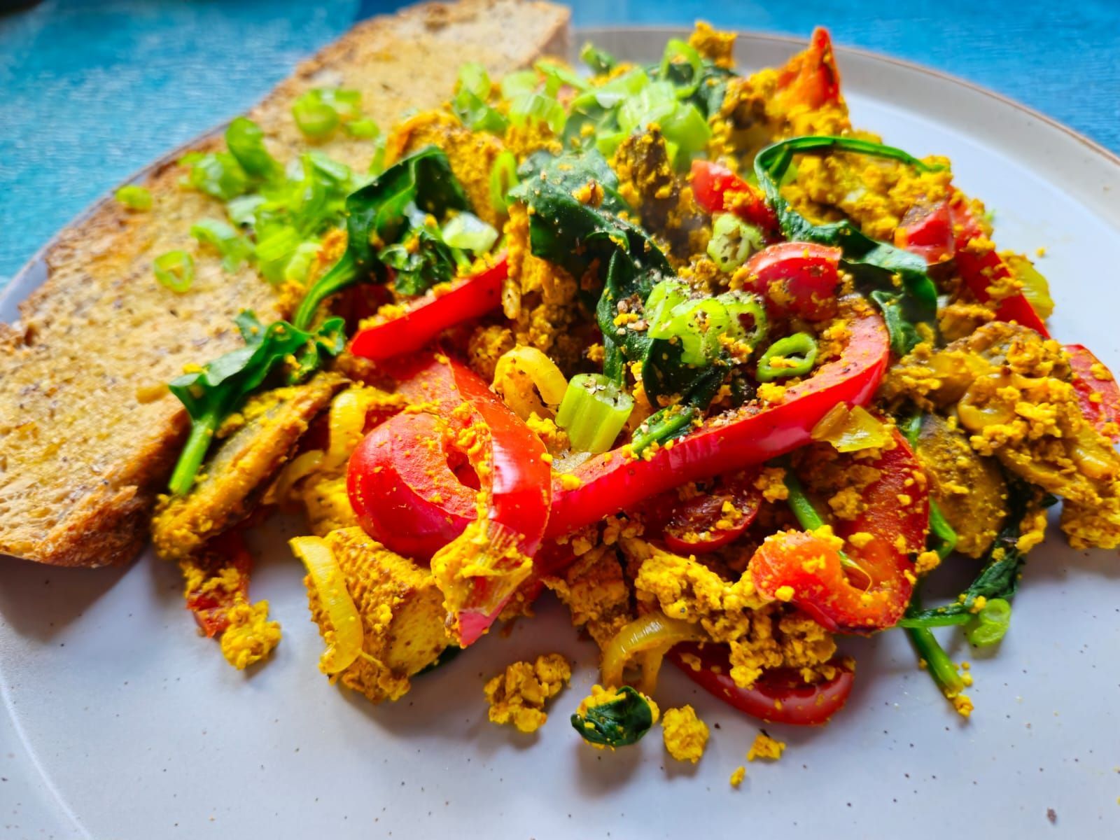 Smoked tofo scramble on a plate with bell pepper and a slice of buttered toast