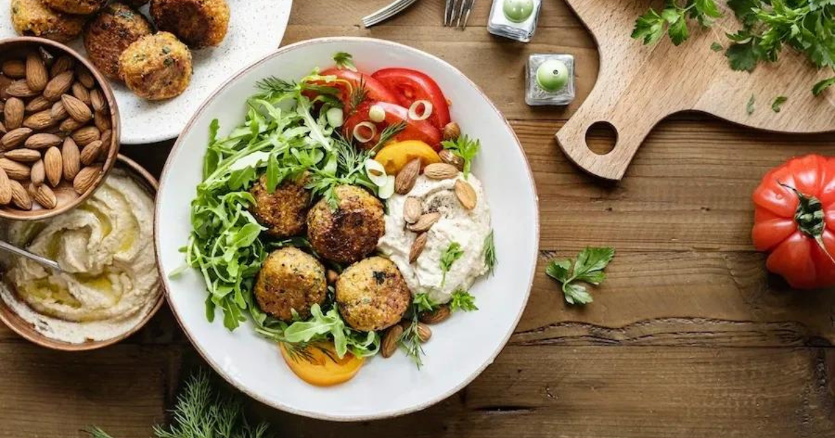 buddha bowl with falafels salad with nuts and tomatoes on a plate with various other dishes with hummus, falafels and fresh herbs