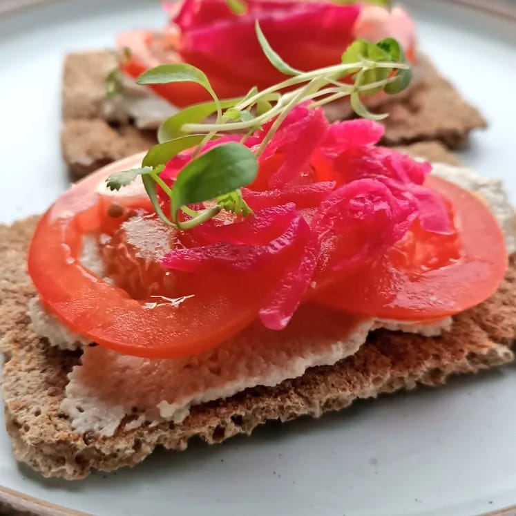 Cheese on crackers with tomato, kimchi, and fresh coriander sprouts