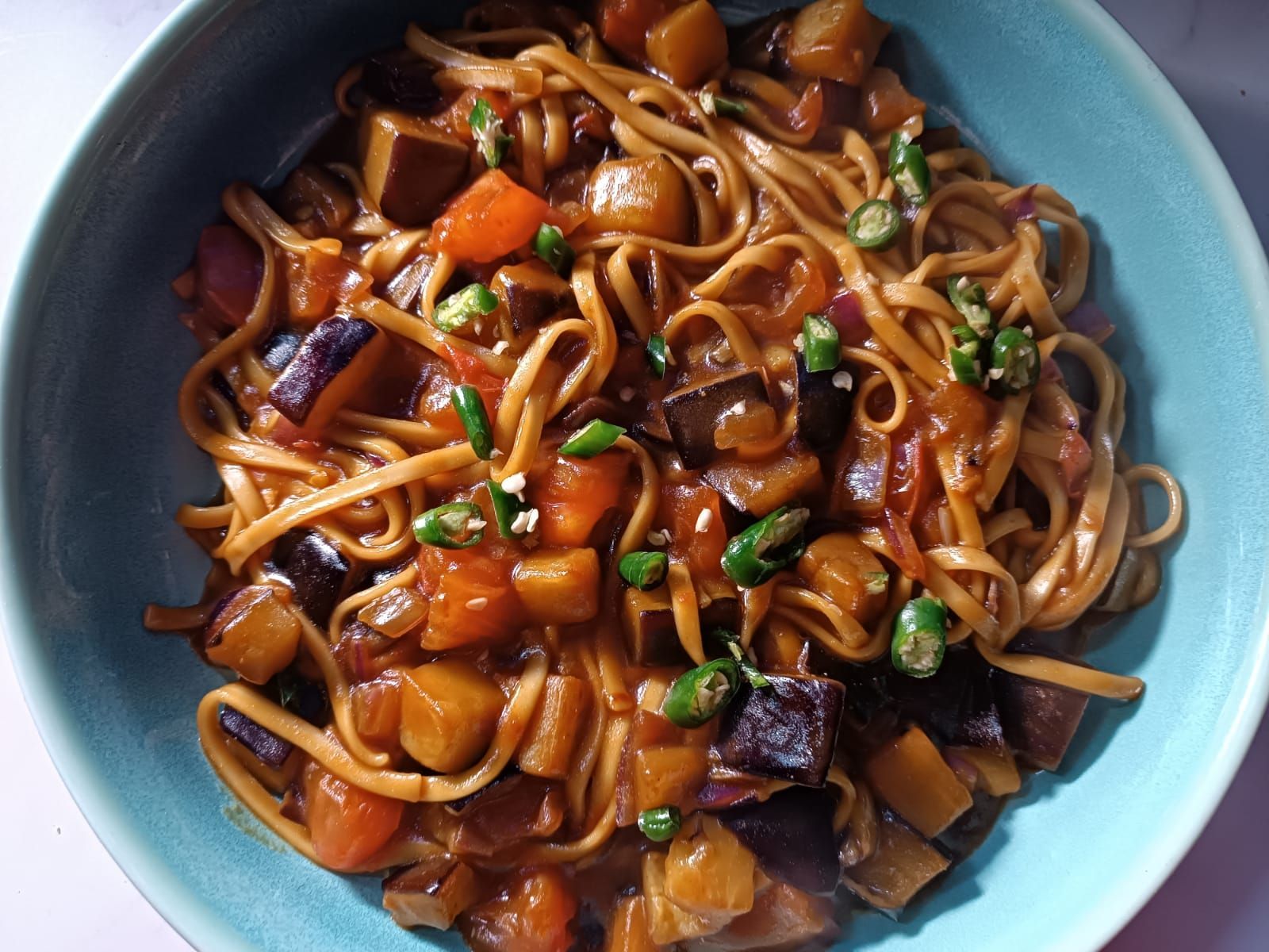 aubergine and noodle stir-fry topped with sliced green chili