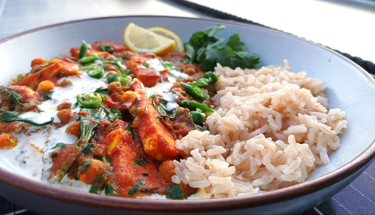 a tofu tikka curry served with brown rice and a spicy tomato sauce