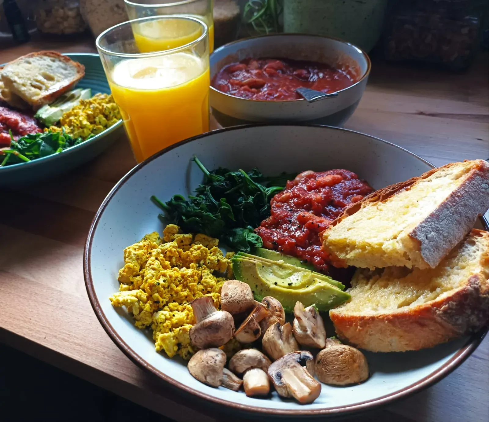 cooked vegan breakfast with tofu scramble home-style beans, avocado, mushrooms and toast