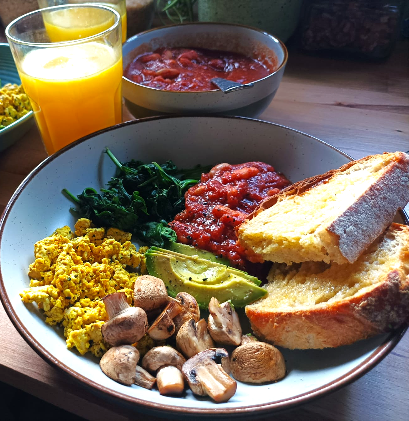 A cooked breakfast with beans, toast, avocado, tofu scramble, and spinach
