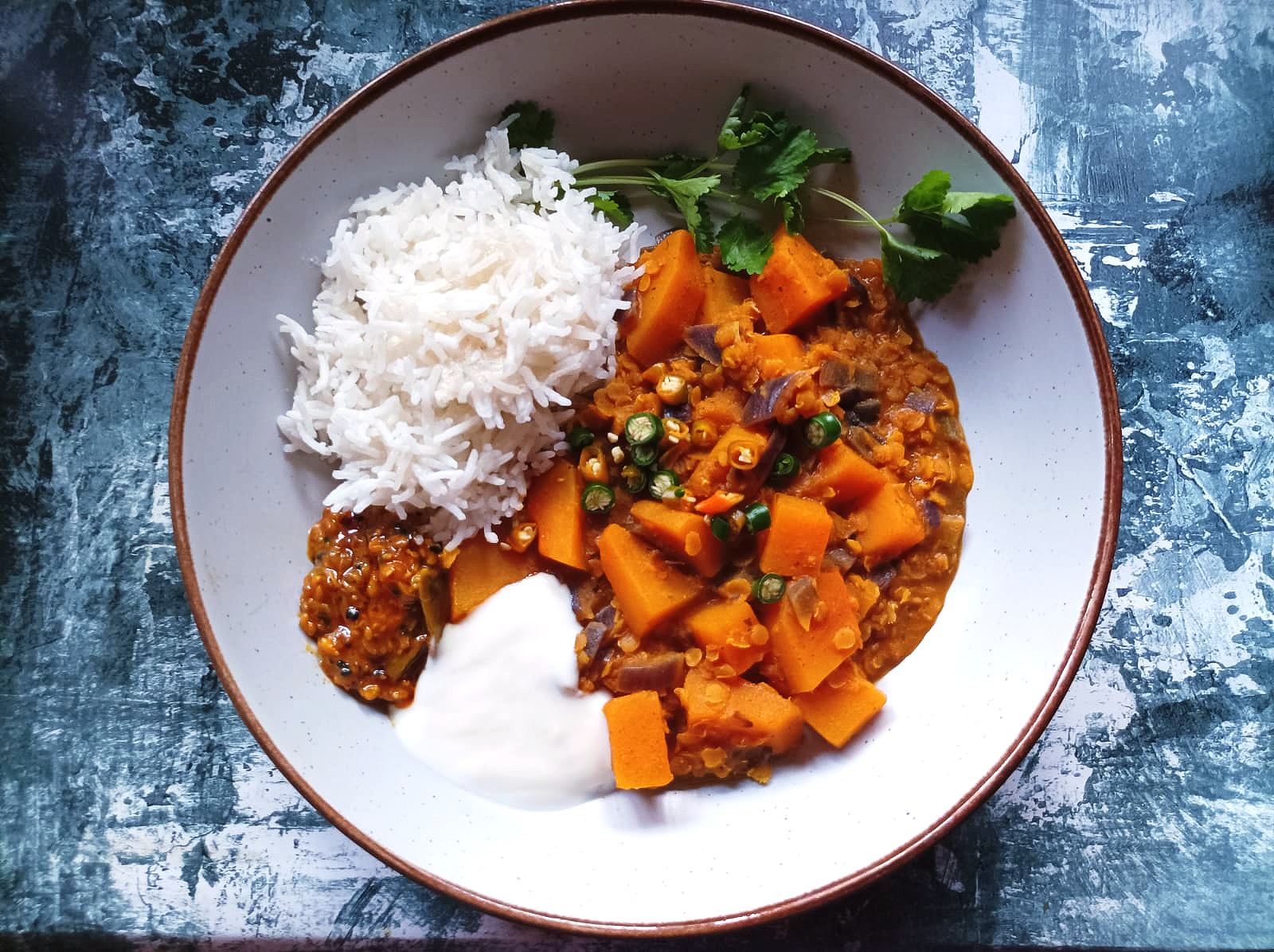 Lentil Dal with butternut squash in a bowl with rice, yogurt, and lime pickle