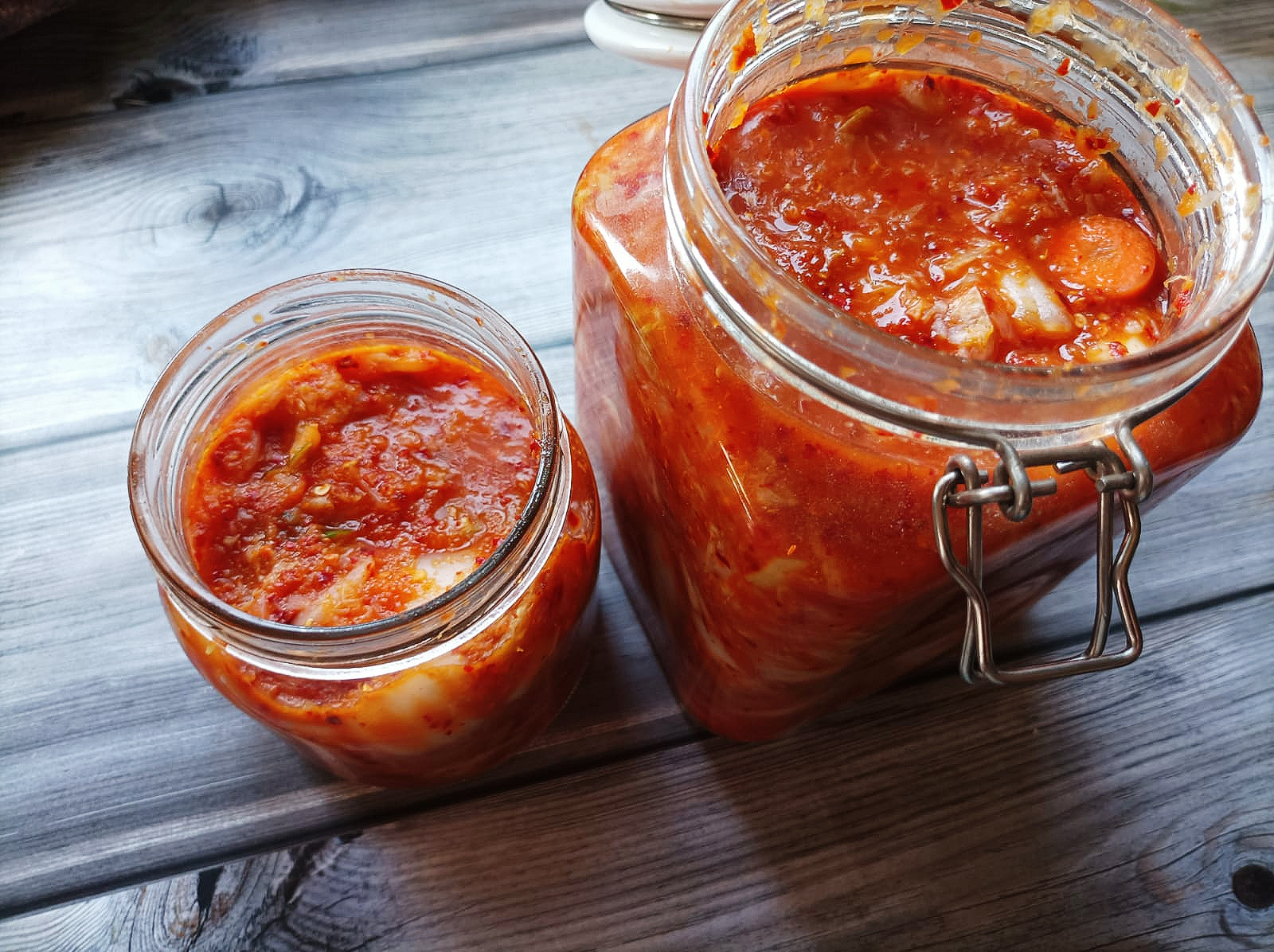 Homemade Kimchi in a large jar next to a smaller jar of kimchi