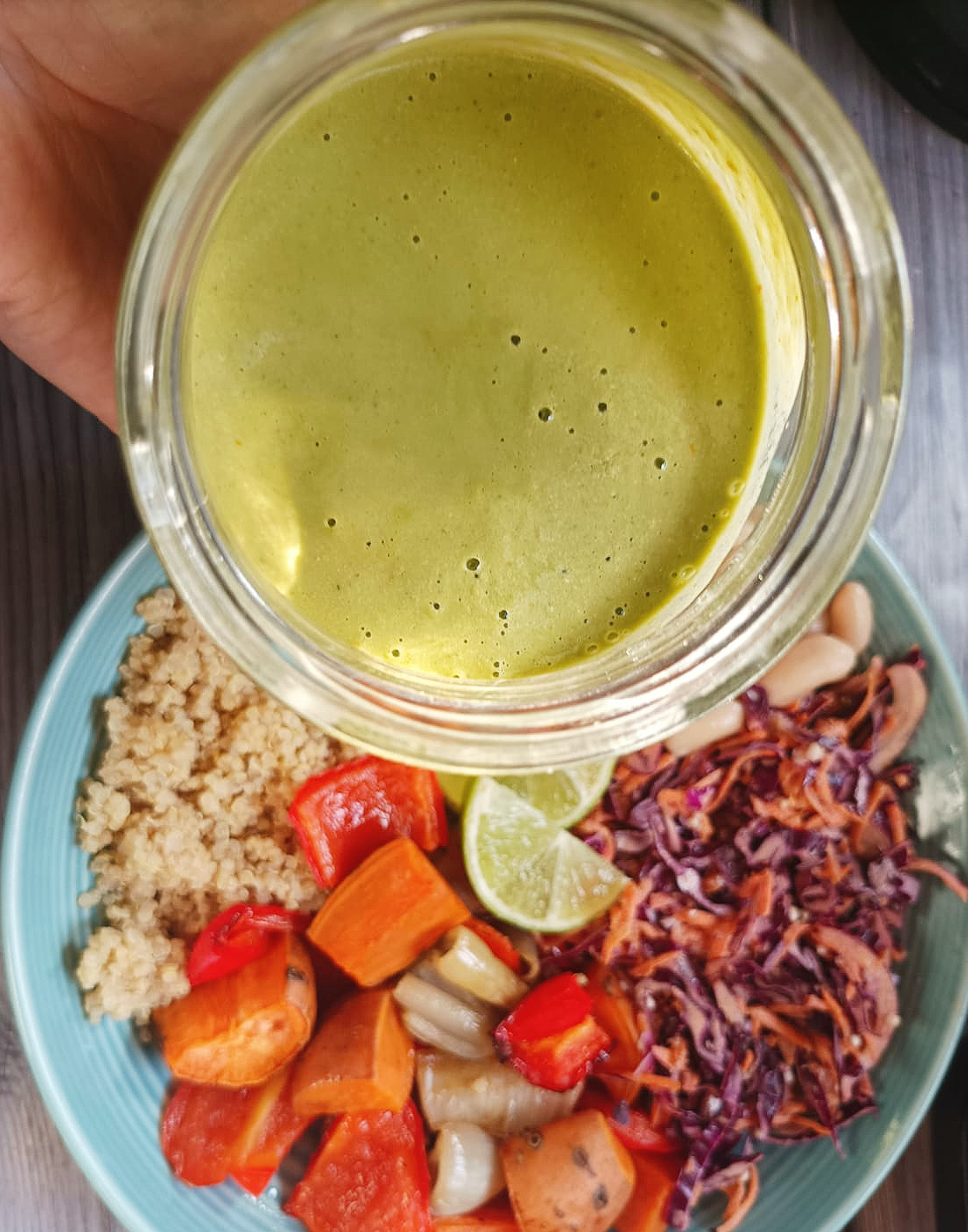 pot of salad green dressing over a bowl of veggies and salad