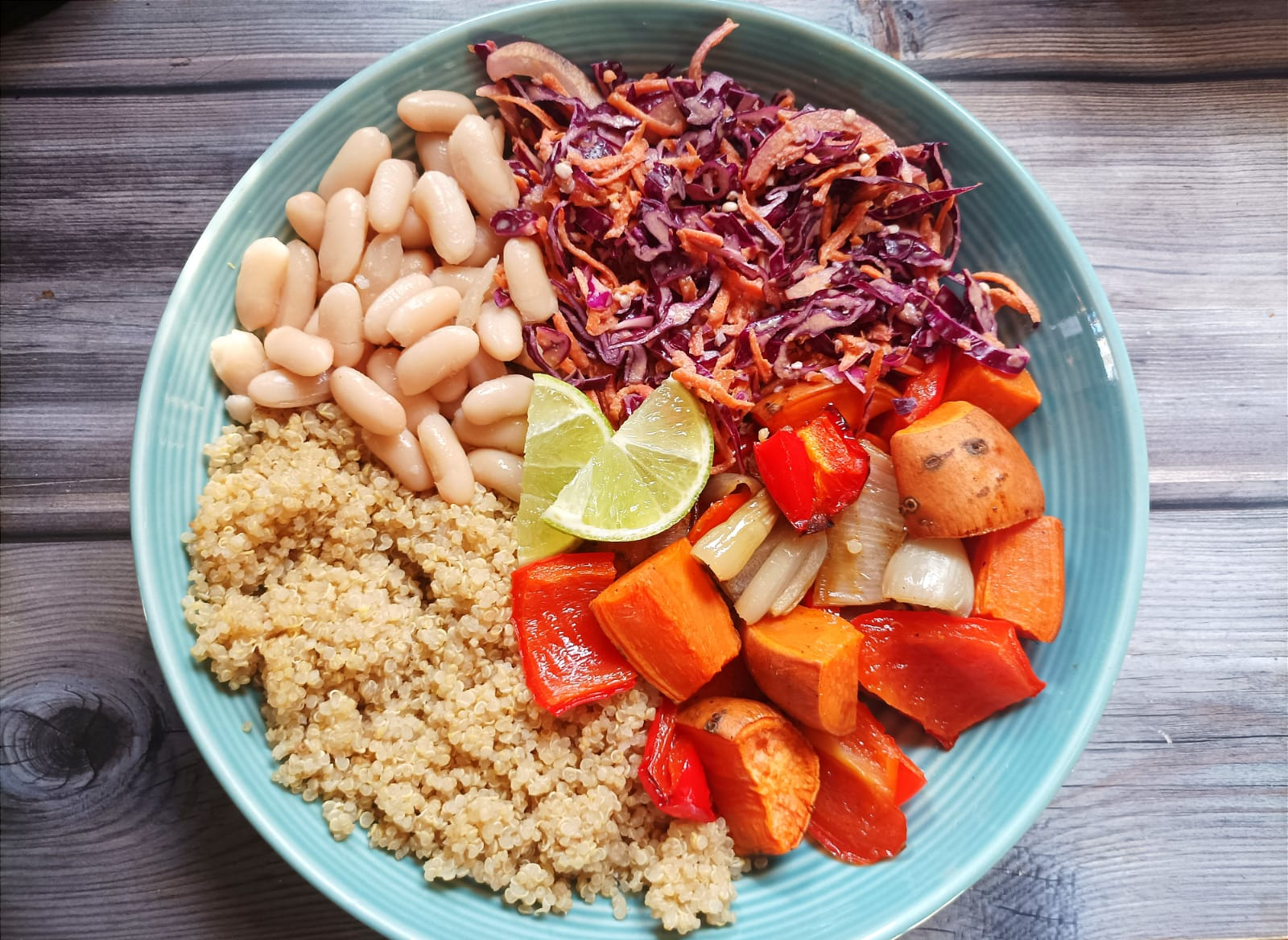 buddha bowl with slaw, beans, quinoa, and roasted veggies. Topped with lime slices