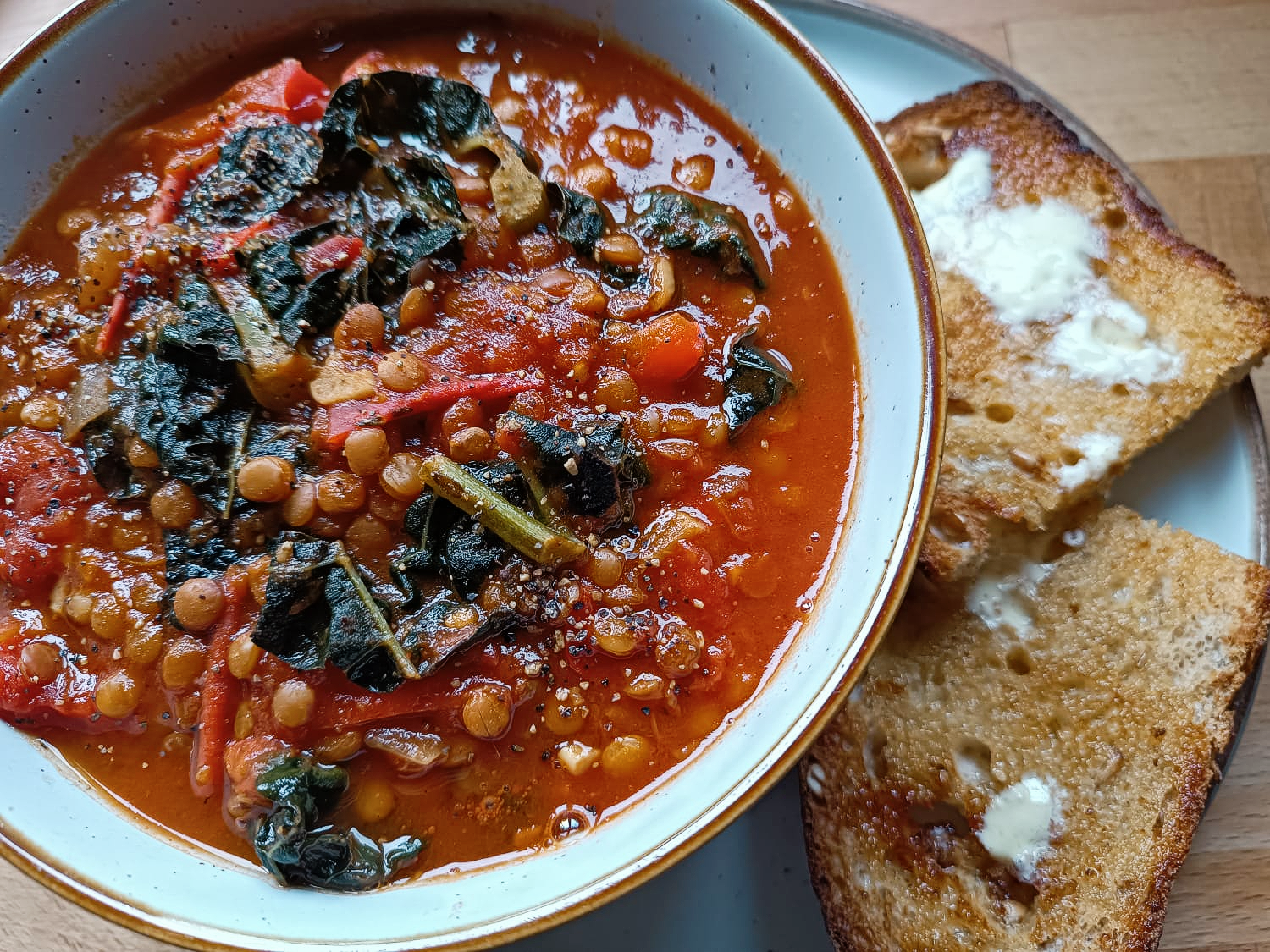 kale and lentil soup in a bowl with buttered toast