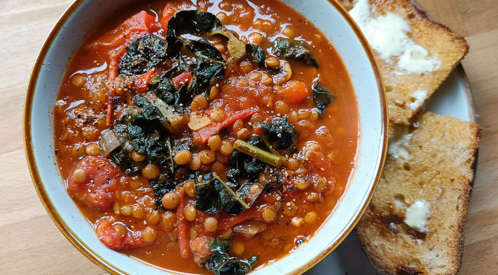 kale and lentil soup in a bowl with buttered toast