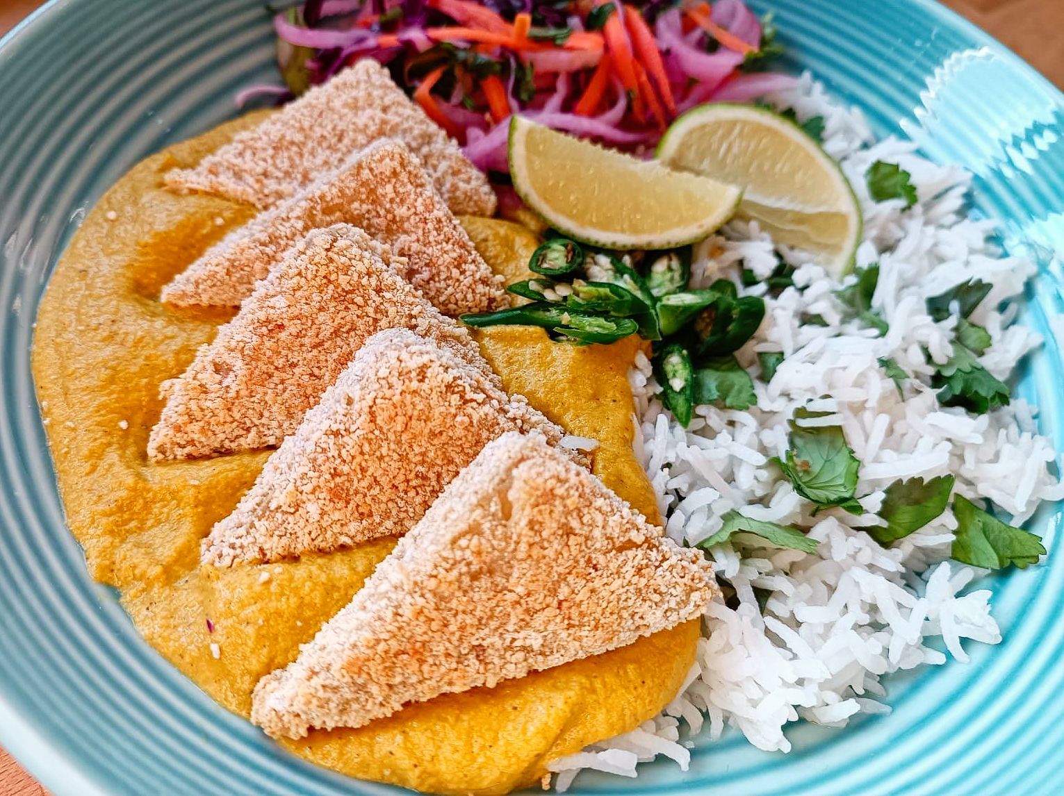 tofu katsu curry with tofu triangles, white rice, and colourful slaw