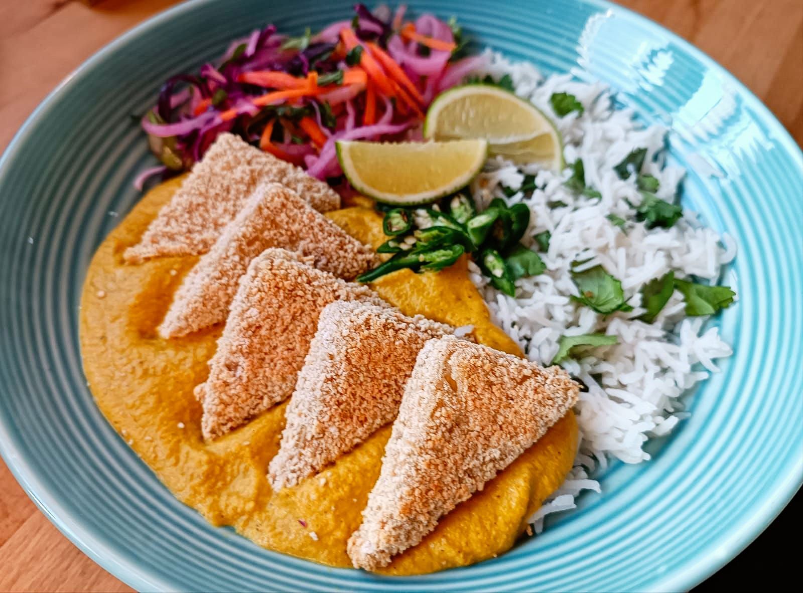 tofu katsu curry with tofu triangles, white rice, and colourful slaw