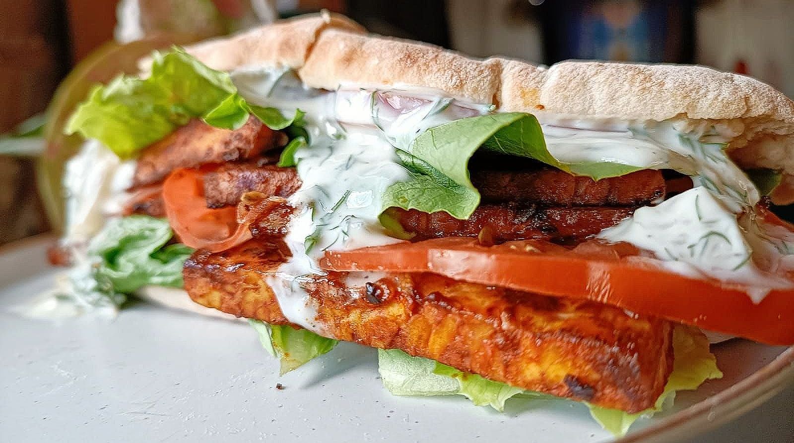 tempeh blt in a pita bread with tomato, lettuce, and dill pickle sauce