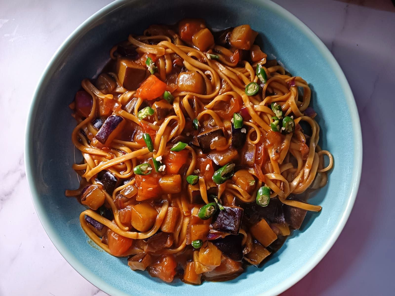 Noodles in a bowl with stir-fried aubergine and tomatoes