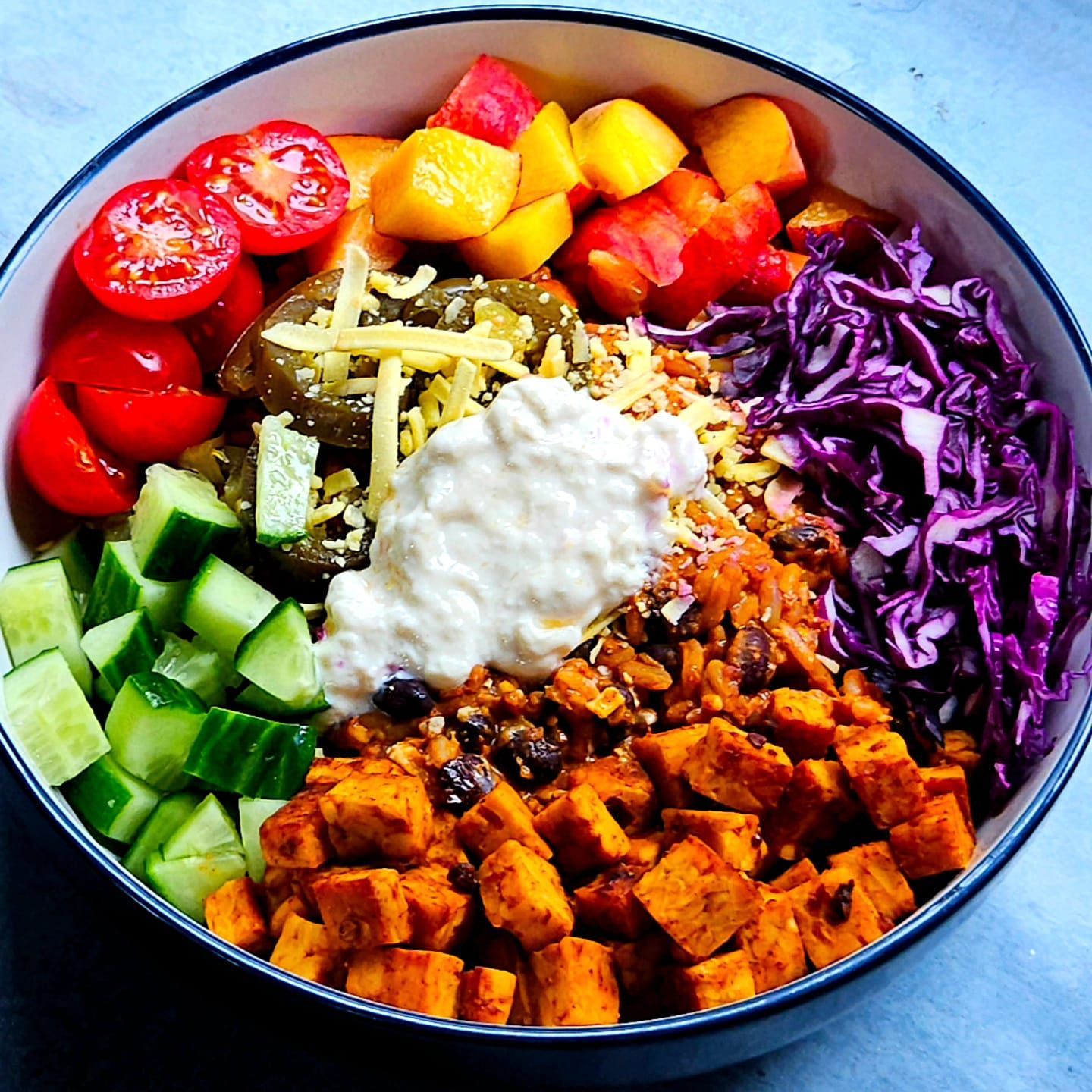 chipotle tempeh mexican bowl with jalapenos, vegan cheese, red cabbage, and yogurt.