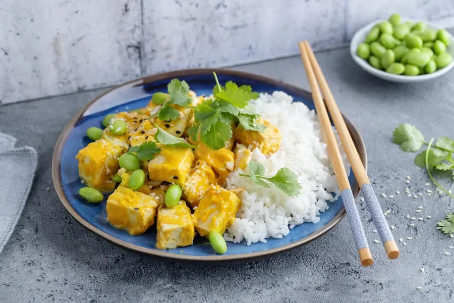 tofu curry on a plate with rice and chopsticks