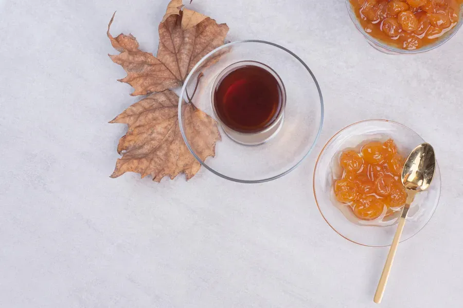 maple syrup on a table with maple leaves and a plate with dried apricots