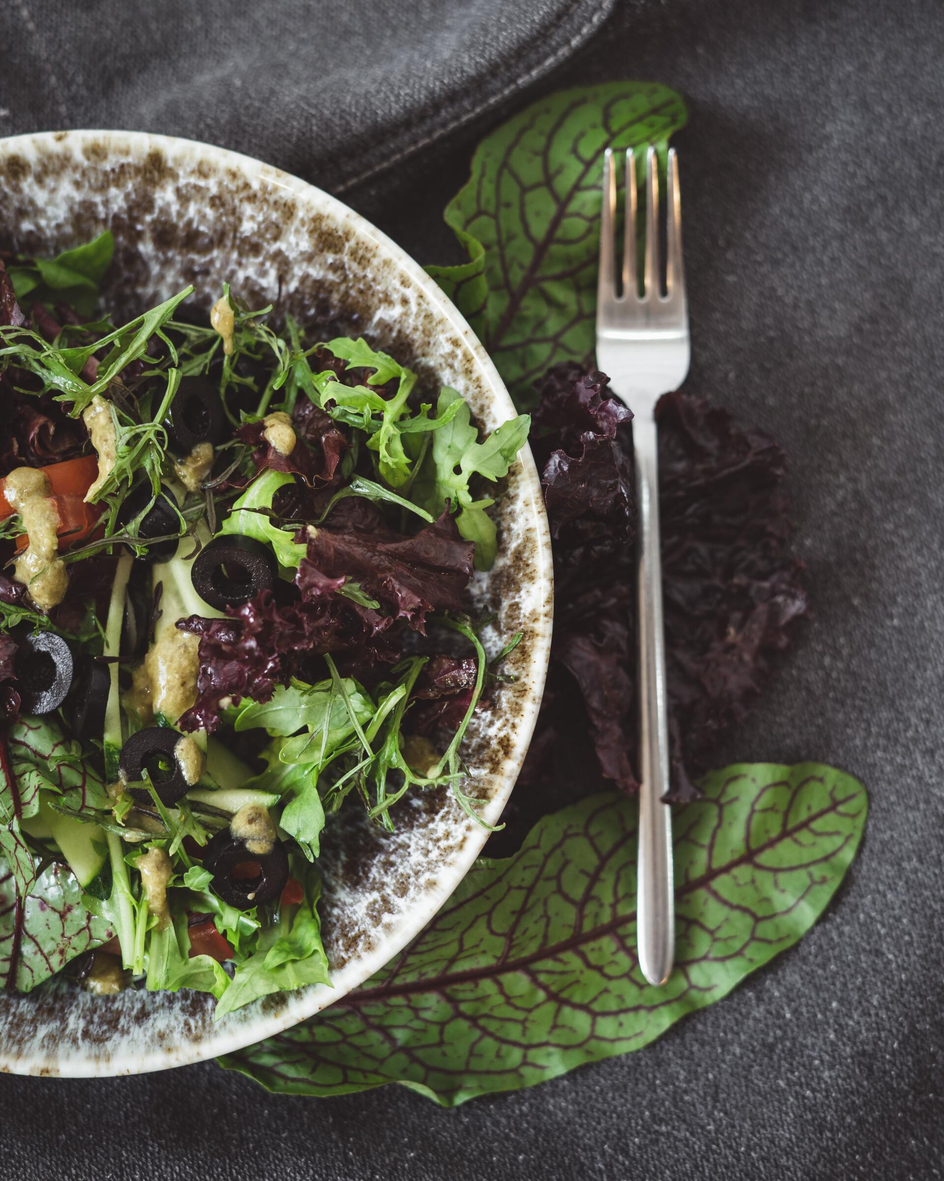 a leafy green salad in a bowl next to a fork