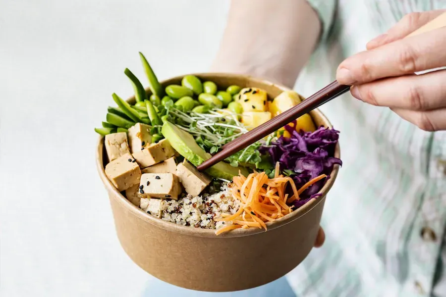 Asian buddha bowl with fresh veggies, quinoa, edamame, tofu, and avocado