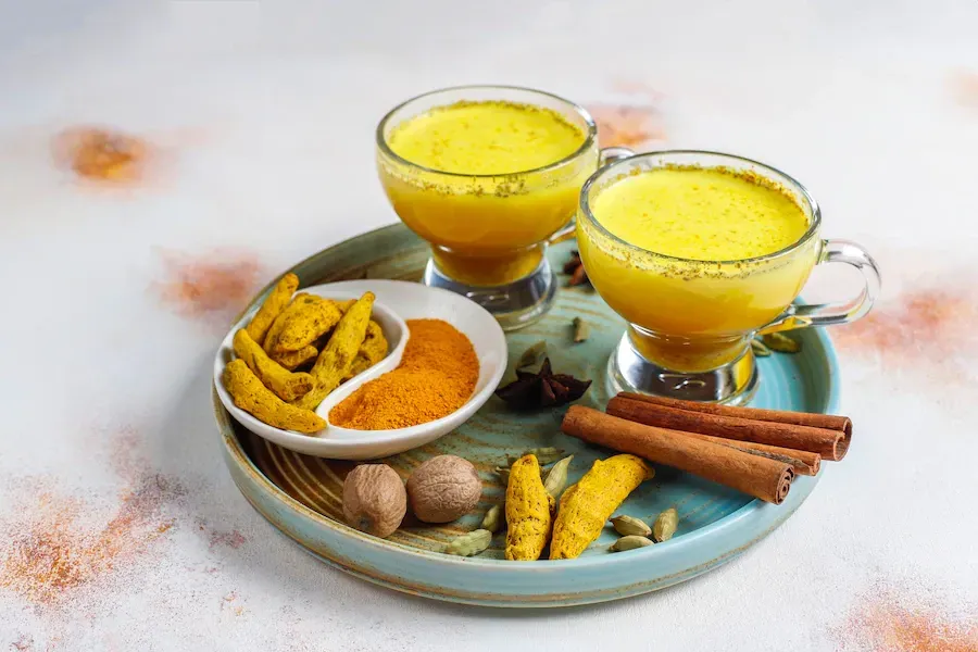 turmeric latte in glasses surrounded by spices