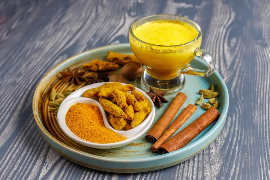 turmeric latte in glasses surrounded by spices