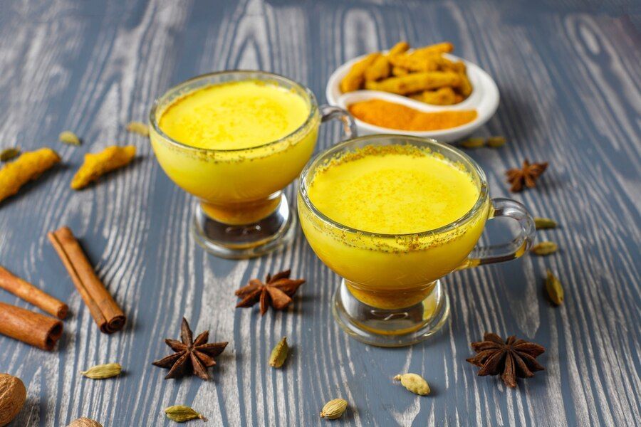 turmeric latte in glasses surrounded by spices
