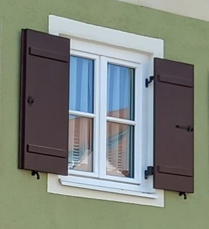 Brettladen mit Gratleisten auf der Tagseite als Klappladen montiert mit Kurbelinnenöffner auf Holzfenster mit Wetterschenkel in der Altstadt von Nördlingen