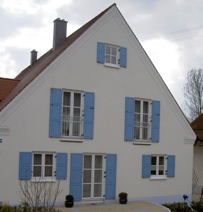 Hausansicht mit blauen Holzfensterläden mit Füllungen