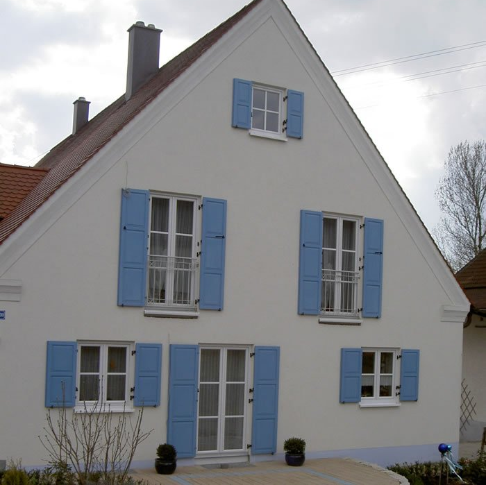 Hausansicht mit blauen Holzfensterläden mit Füllungen