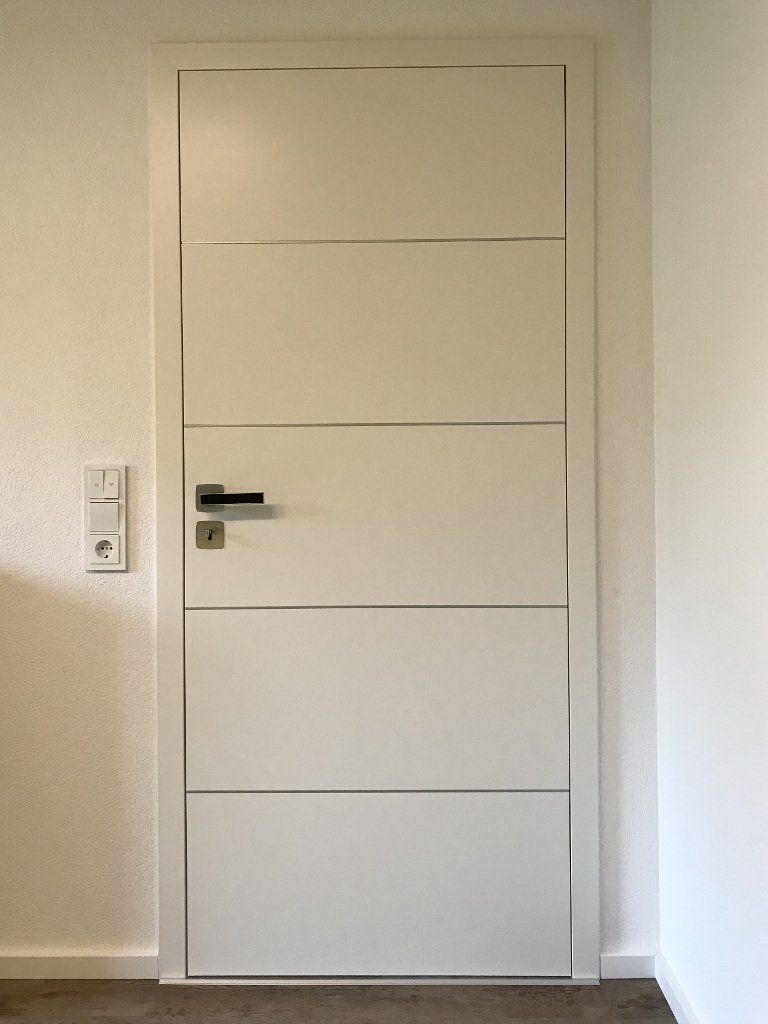 Weiß lackierte stumpf einschlagende flächenbündige Zimmertüre mit Lisenen